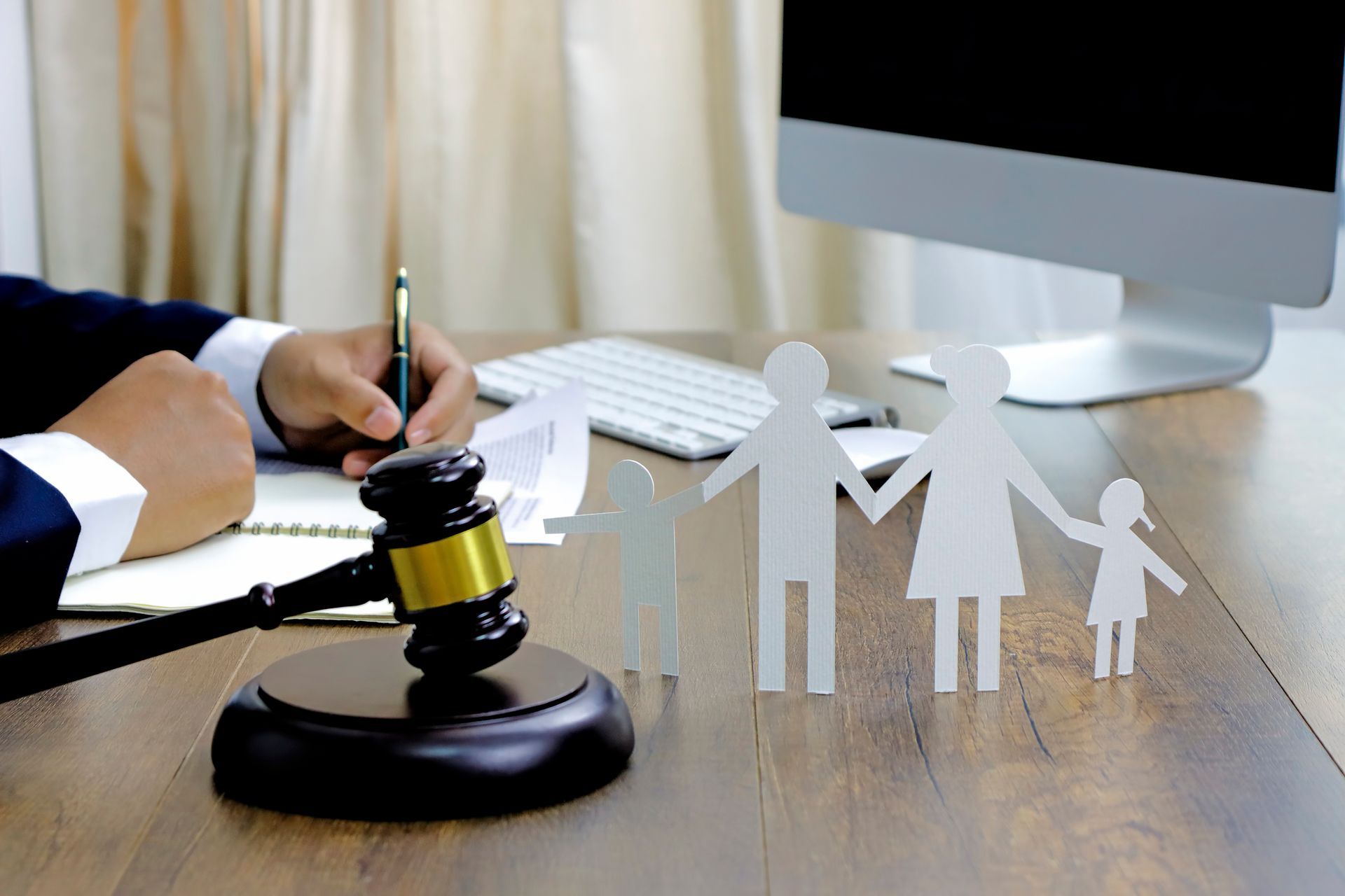 A lawyer writing at a desk with a gavel and paper family cutouts, symbolizing the family law concept