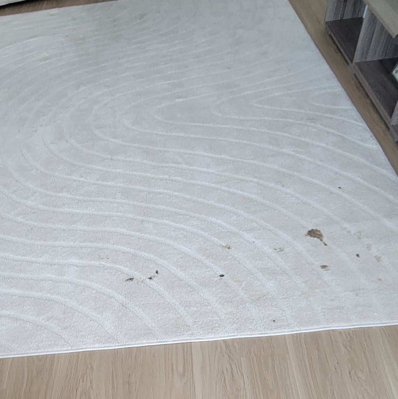 A white rug is sitting on a wooden floor in a living room.