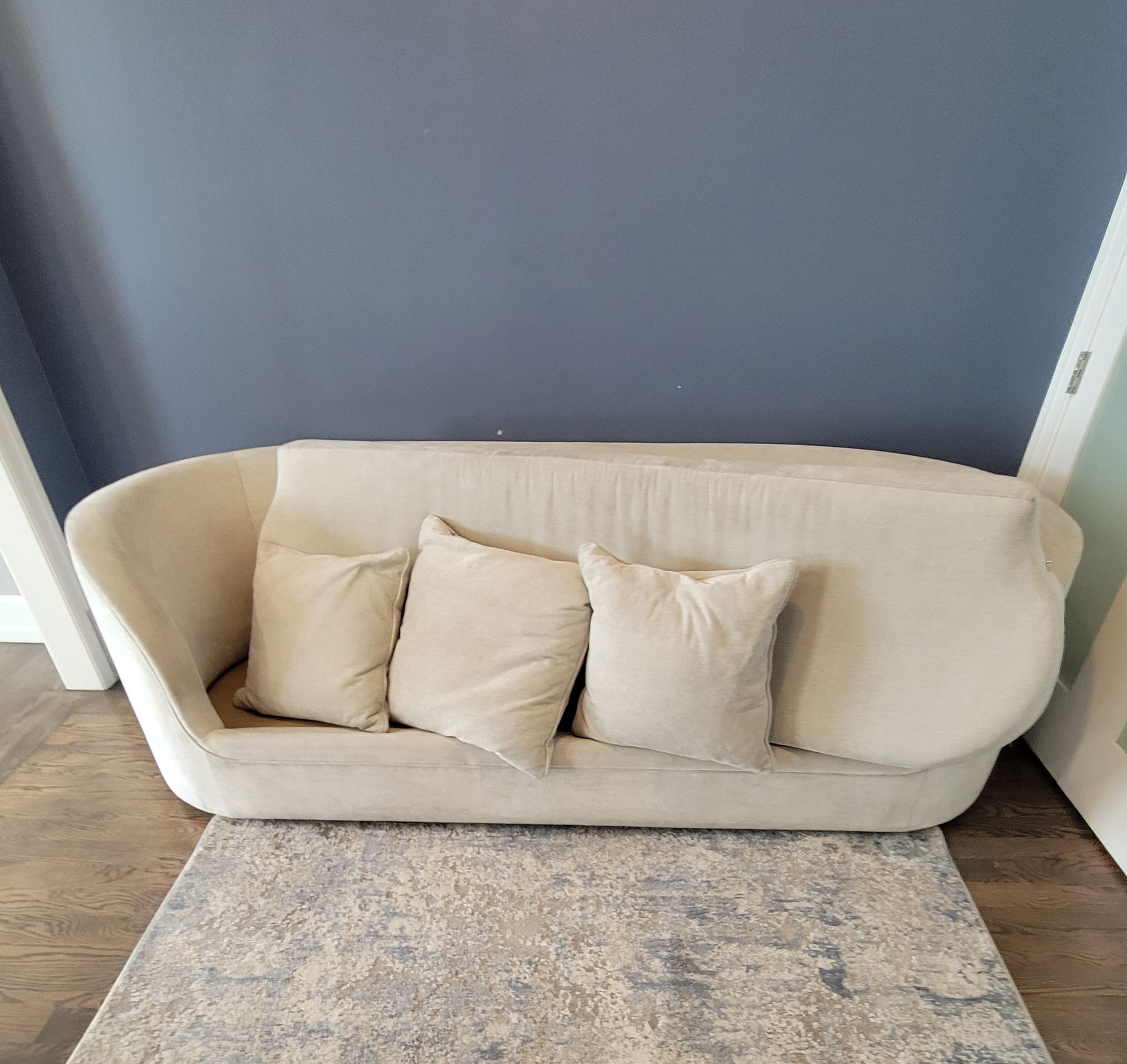 A white couch with white pillows is sitting on a rug in a living room.