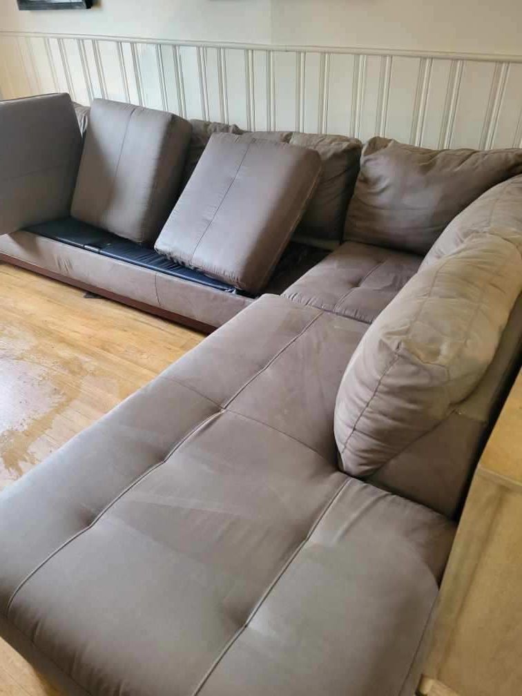 A couch is sitting in a living room next to a wooden wall.