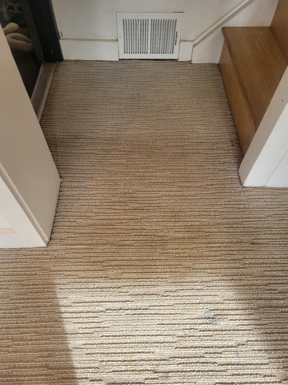 A carpeted floor in a room with stairs and a fireplace.