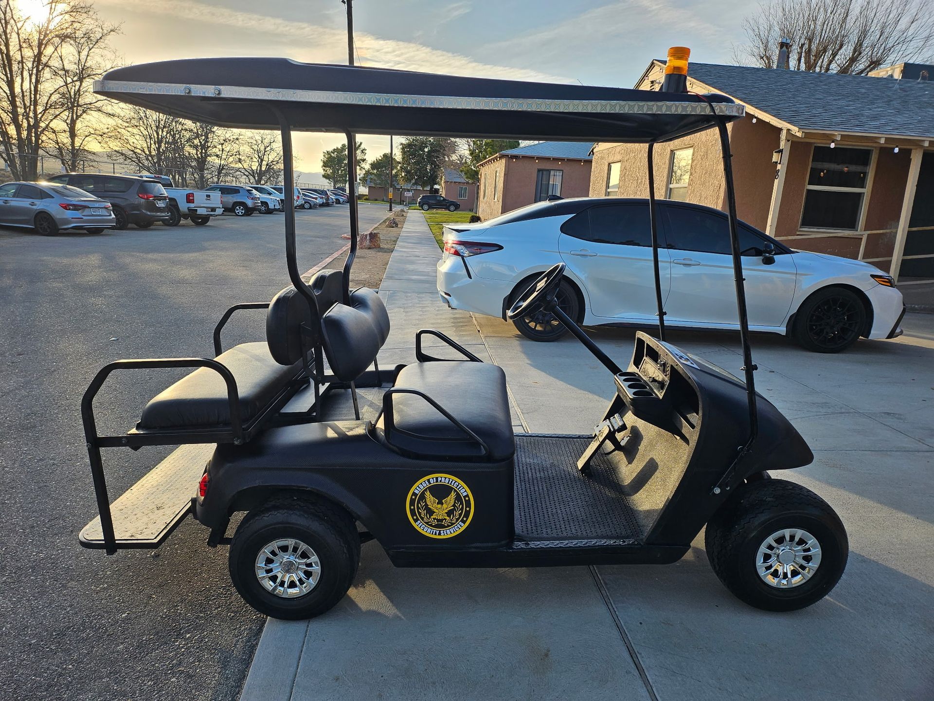 Person standing beside a marked patrol car in a parking lot outside a beige building.