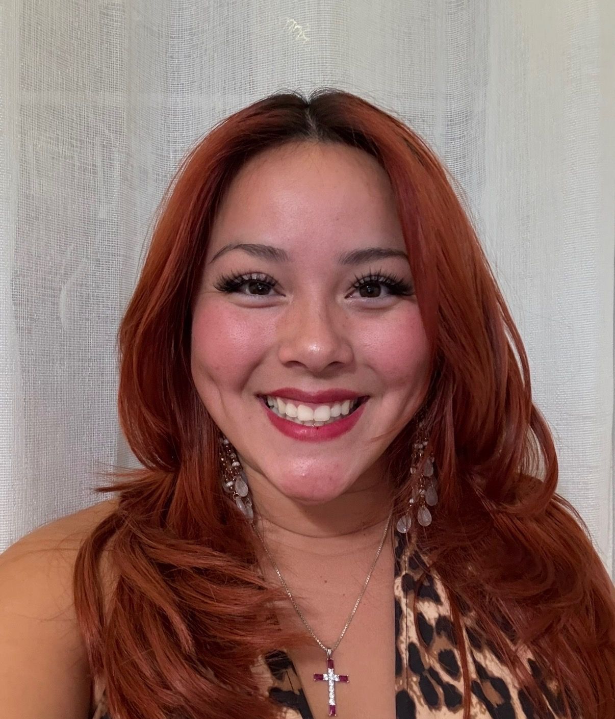 Professional portrait of a woman in a navy blazer and white blouse, smiling in a hallway