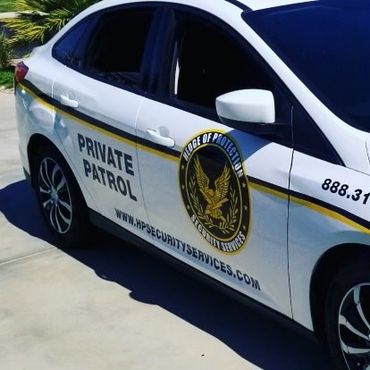 White security patrol car with gold stripe and company logo parked outdoors.