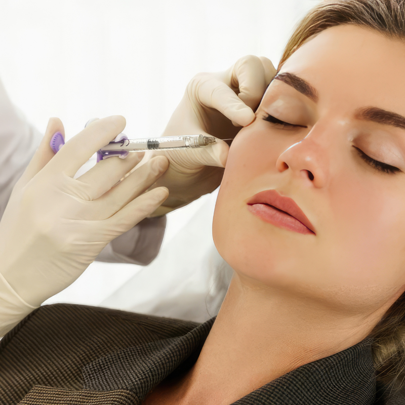 Cosmetic injection being administered to a woman’s cheek by gloved hands in a clinical setting