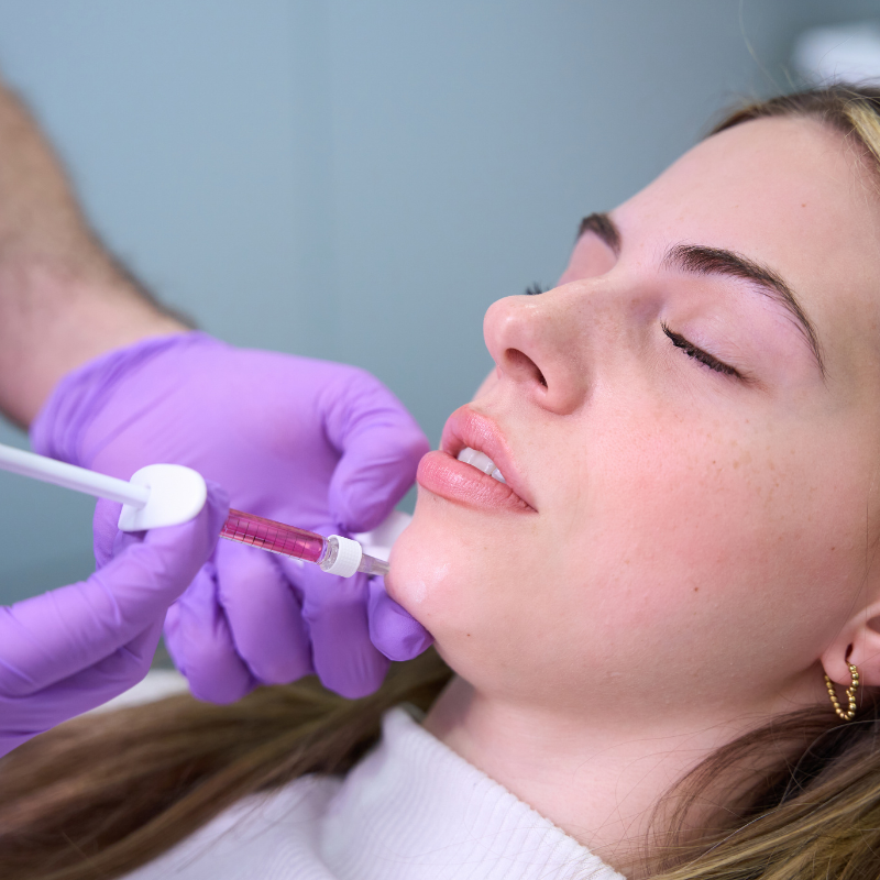 Dentist wearing purple gloves applying a dental tool to a patient's mouth