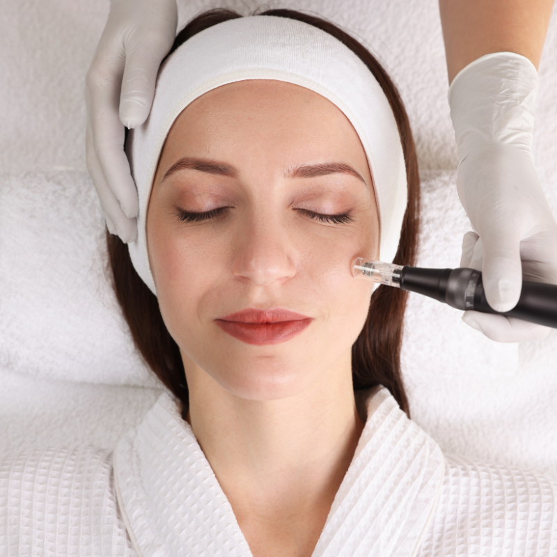 Facial treatment with a woman lying on a spa bed while a gloved hand uses a device on her cheek