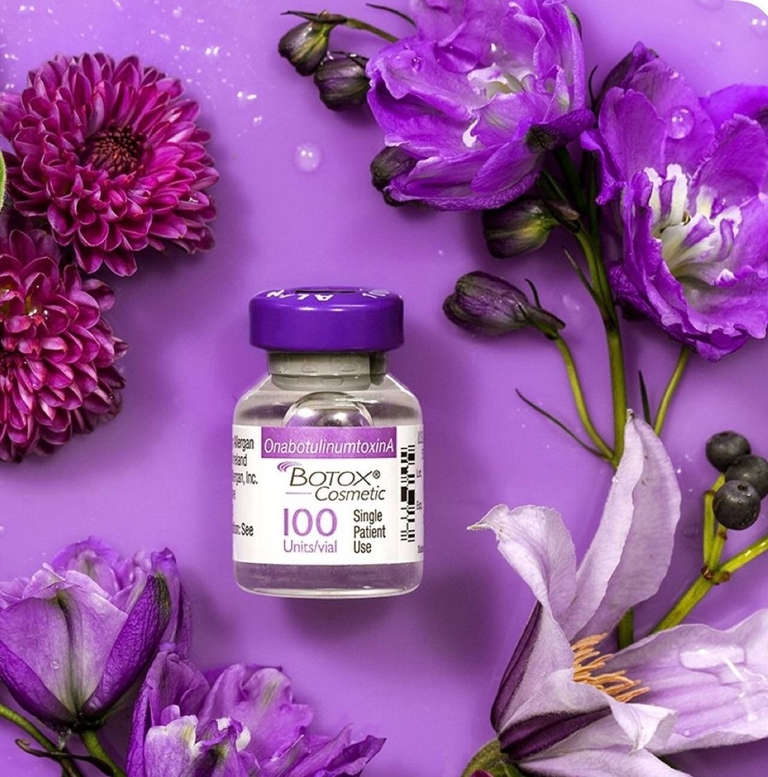 Purple floral arrangement with a small lavender supplement bottle on a violet background