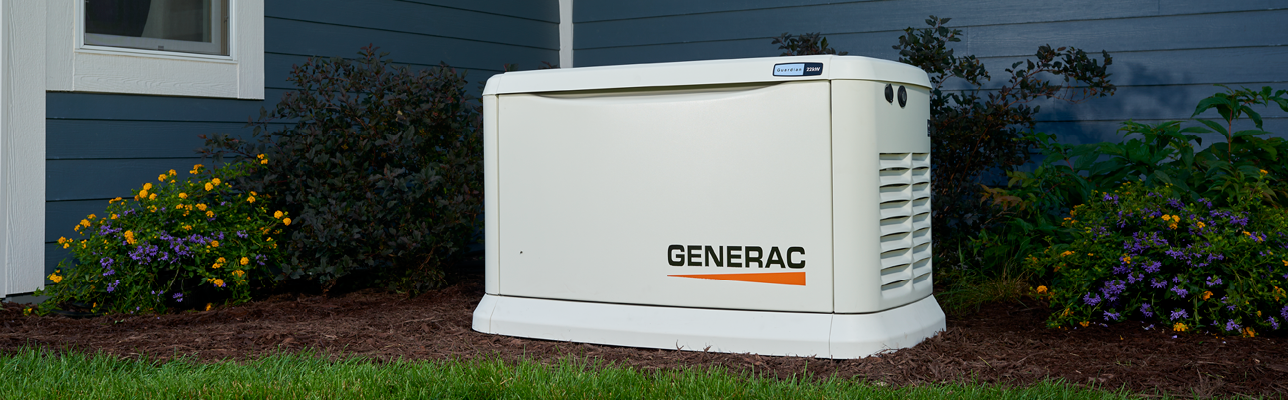 A generator is sitting in the grass in front of a house.