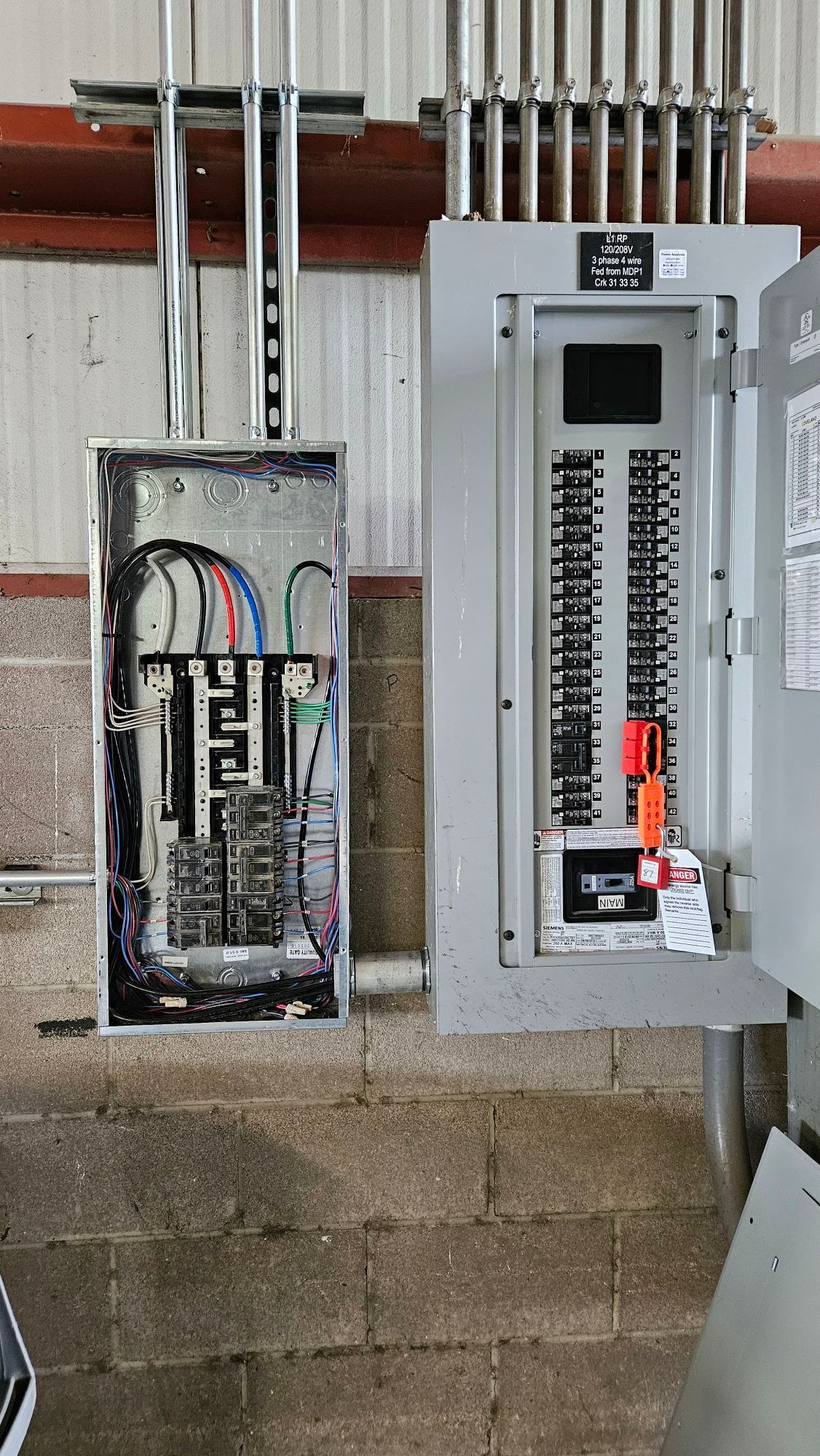 Two electrical panels are sitting next to each other on a brick wall.