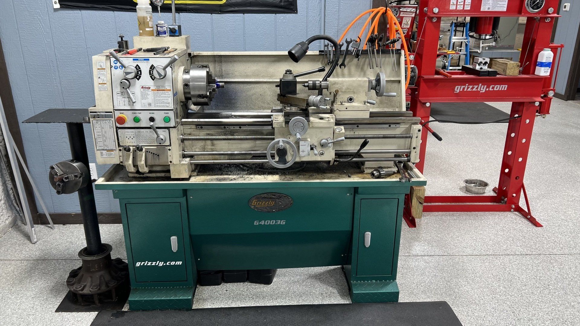 A lathe is sitting in a room next to a red press