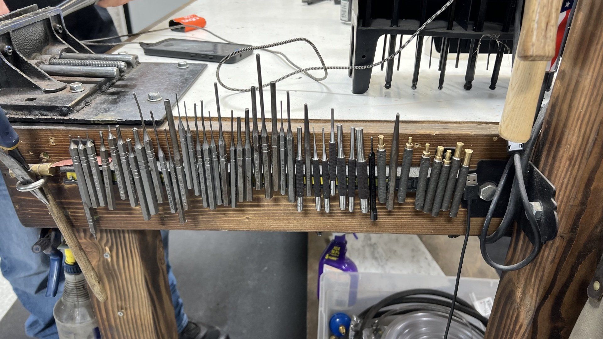 A bunch of drill bits are sitting on a wooden table.