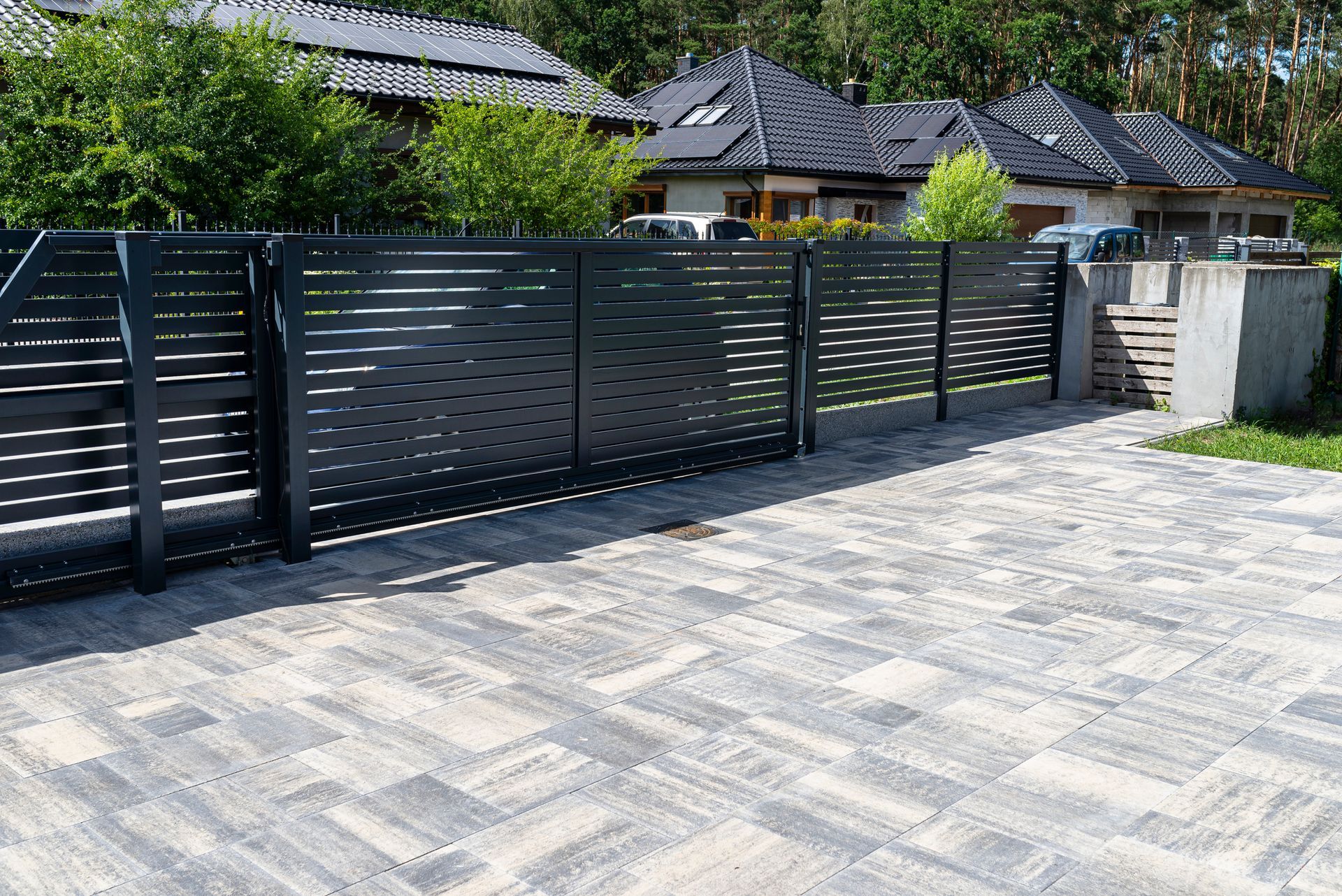 A black fence is surrounding a driveway in front of a house.