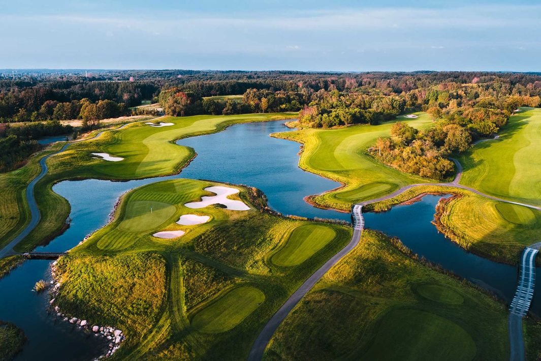 Aerial view of a golf course with winding water hazards, green fairways, and sand bunkers at -Scandinavian New Course