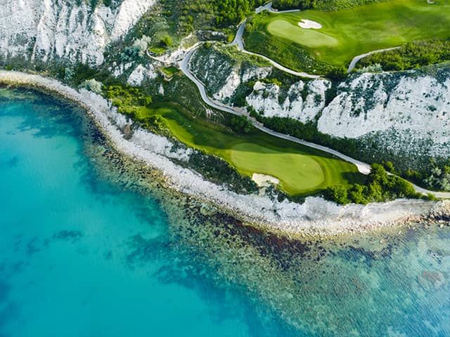 Golf hole at Thracian Cliffs in Bulgaria with white chalk cliffs and the Black Sea stretching beyond