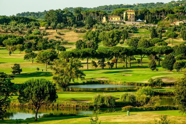 Lush green golf course with sand bunkers, water hazards, at golf club in italy