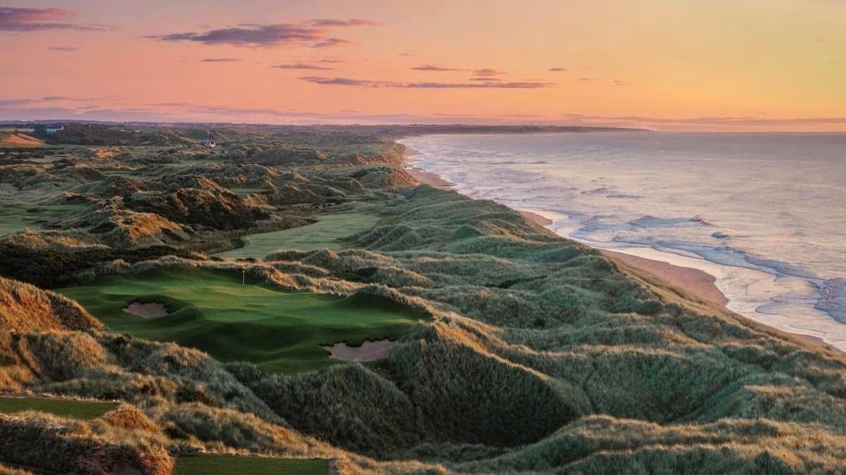 Sunset over Doonbeg golf club grassy dunes beside a calm ocean on Ireland golf tour