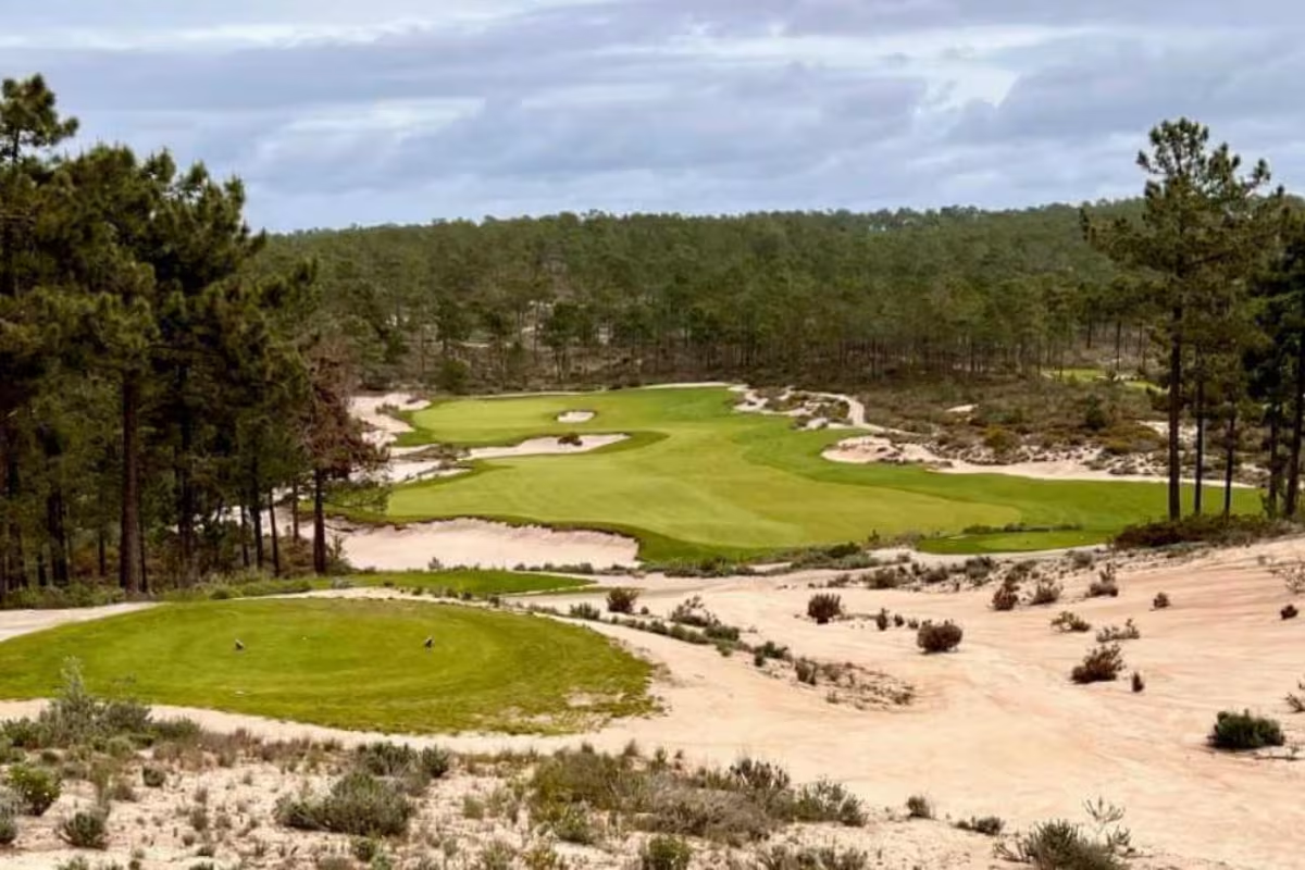 Golf course green fairways bunkers surrounded by pine trees and sand dunes at Dunas golf club on portugal golf tour