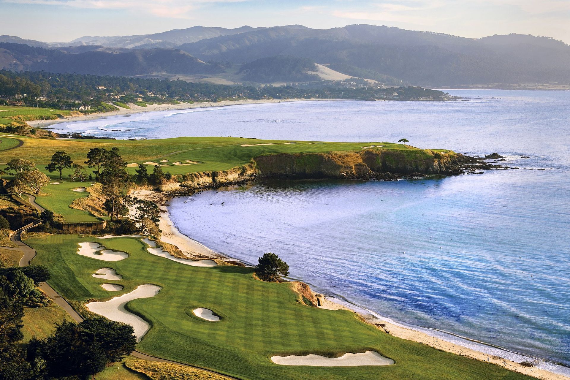 Golfer on the 7th tee at Pebble Beach Golf Links with Pacific waves breaking against the rocks beside the green