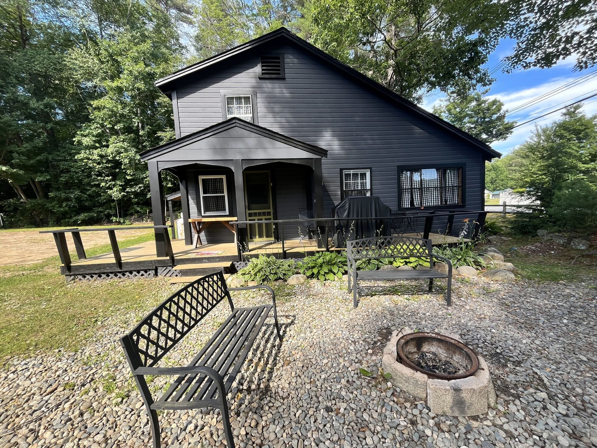 A black lake house with a fire pit in front of it.