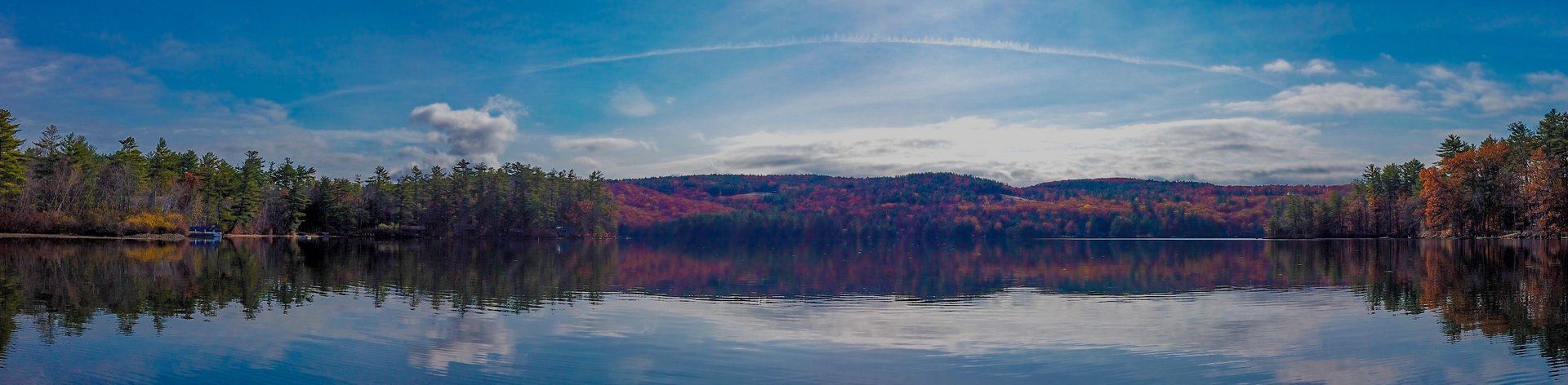 The sun is setting over a lake surrounded by mountains.