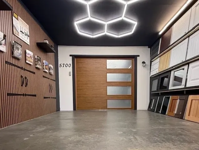 Modern showroom entry with wood cabinetry, geometric ceiling lights, and a frosted glass door