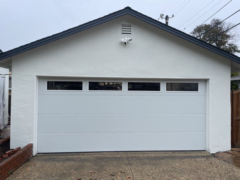 White two-car garage door on a house with small windows and a gabled roof