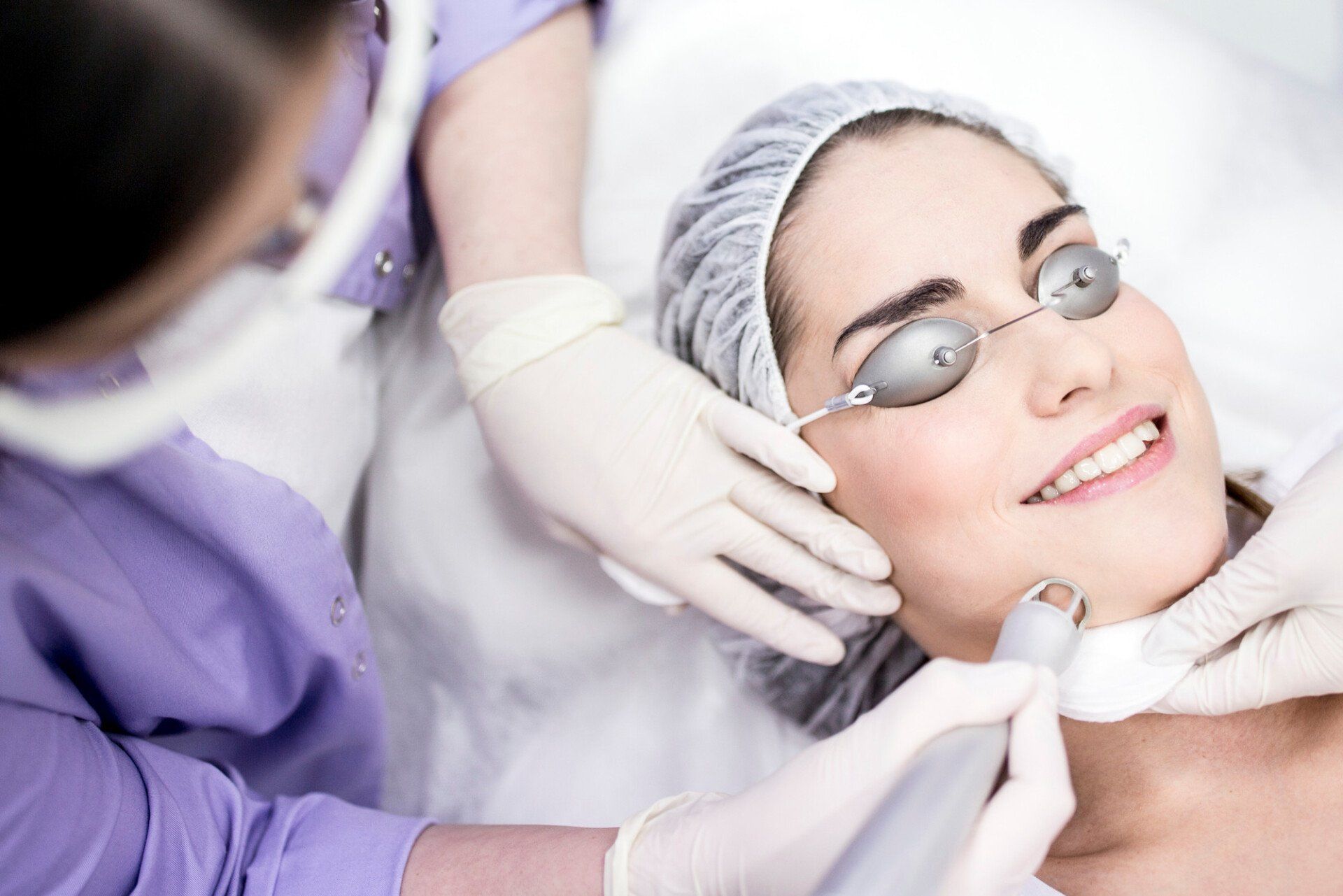 Dermatologist using carbon dioxide laser resurfacing machine on woman's face, close-up. This treatment is used on acne scars, wrinkles, skin pigmentation, warts, and spots.