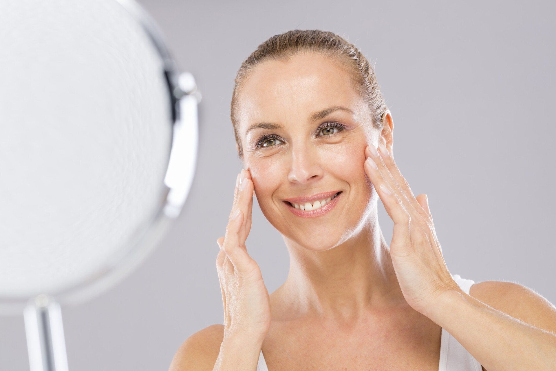 Middle aged woman with care and tenderness face skin looking to the mirro