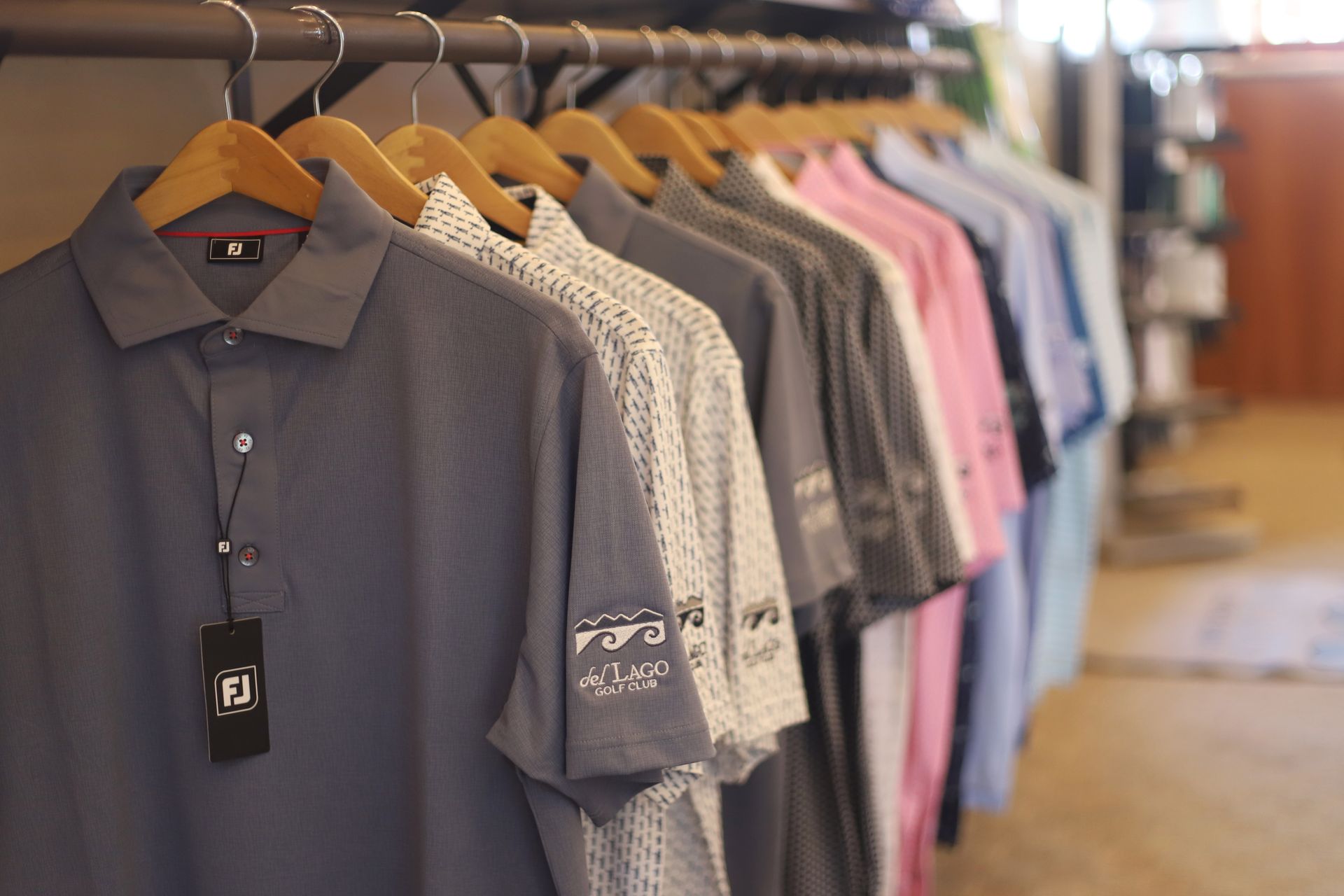 Row of colorful polo shirts hanging on a rack in a store.