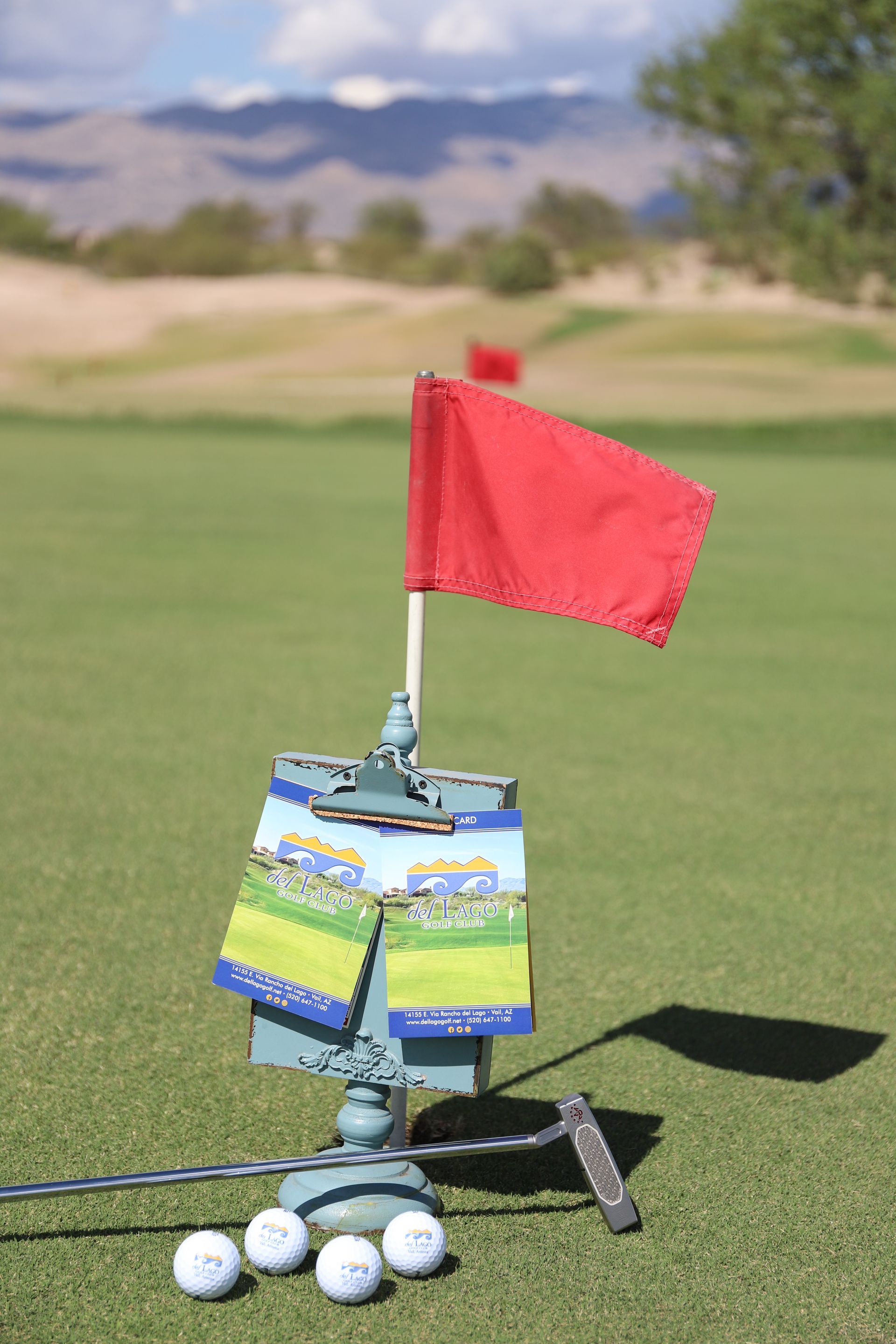 Man in golf attire swings a club on a green course under a blue sky.