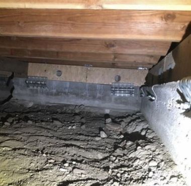 Empty basement with plastic-covered floor, exposed wooden joists, and insulated walls under construction