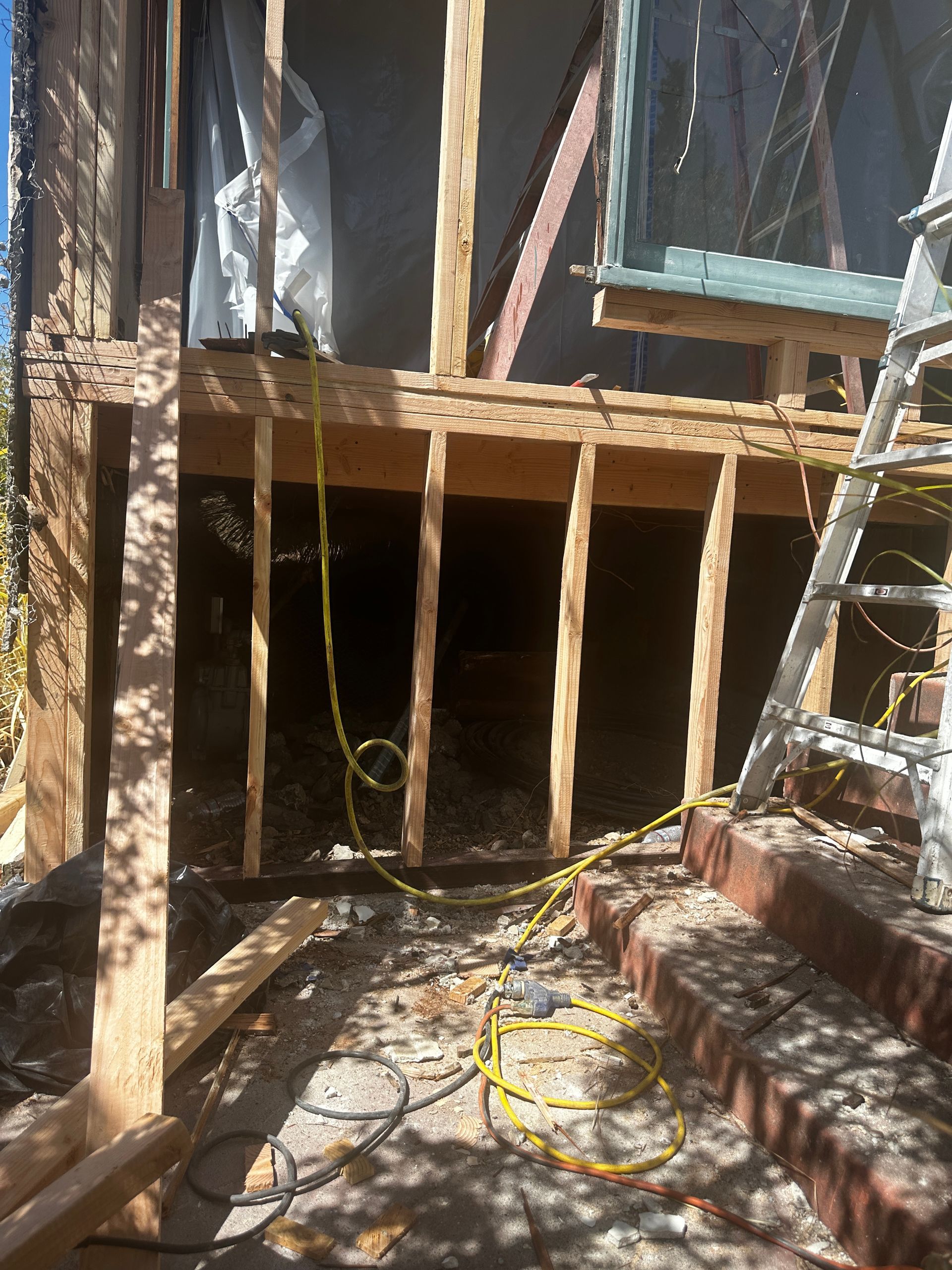 White vapor barrier lining a crawlspace under exposed wooden floor joists