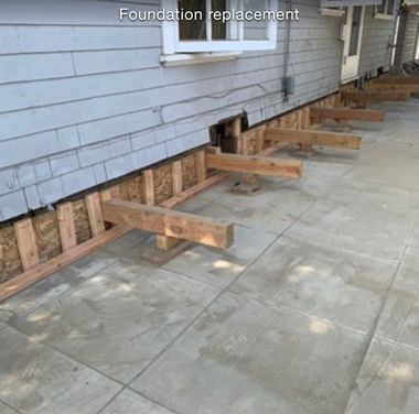 Unfinished basement with concrete foundation walls, exposed wood framing, and white floor covering