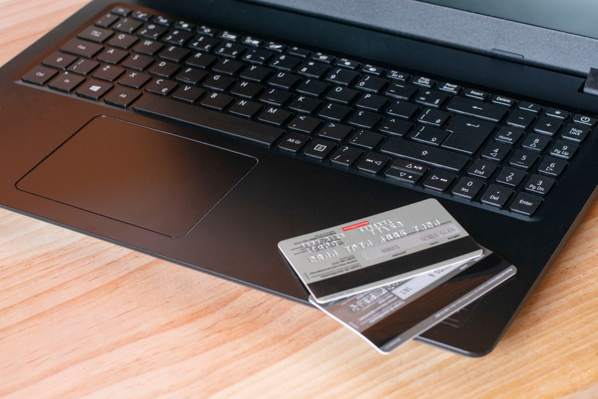 Two Credit Cards Are Sitting on Top of a Laptop on a Wooden Table