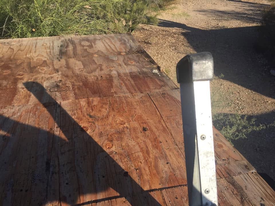 Weathered wooden ramp with a white metal post in a sunlit dirt outdoor setting
