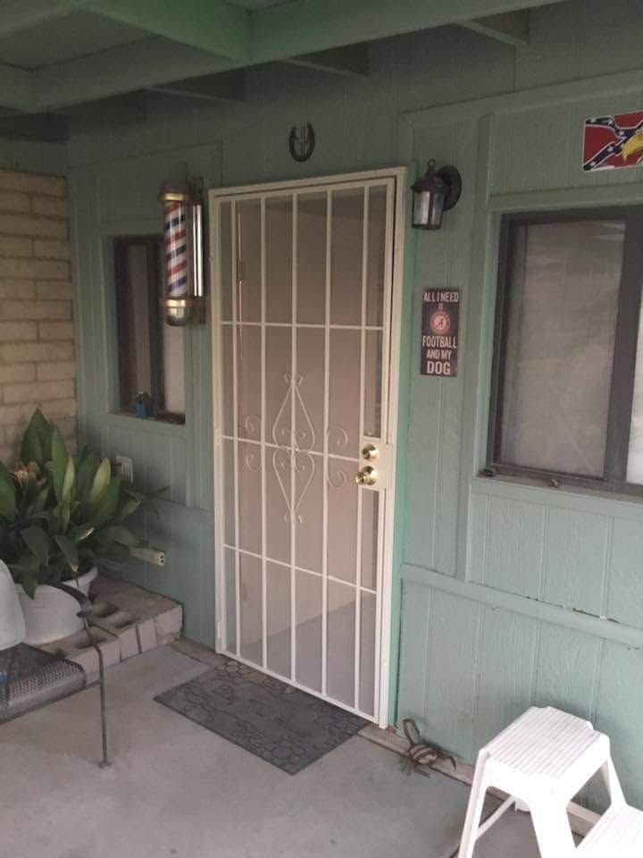 Front porch with a white security door, potted plant, window, doormat, and a white plastic stool.