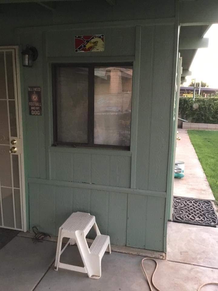 Small green exterior wall with a window, white step stool, and a concrete walkway beside a doorway.