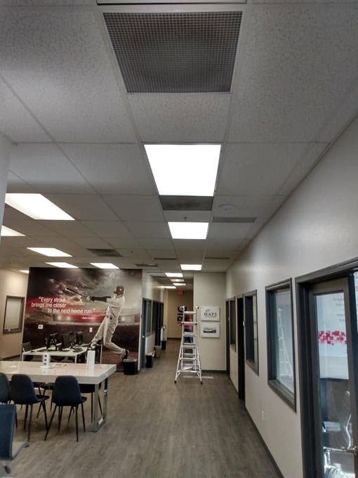 Empty restaurant dining area with tables, chairs, ceiling lights, and a wall of windows and glass doors.