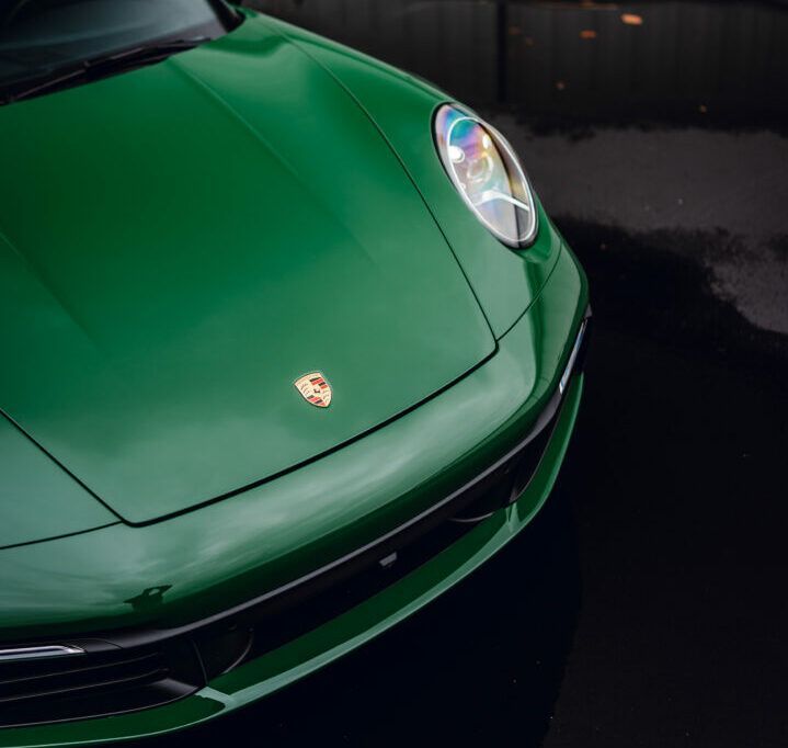 A green porsche is parked in a dark parking lot