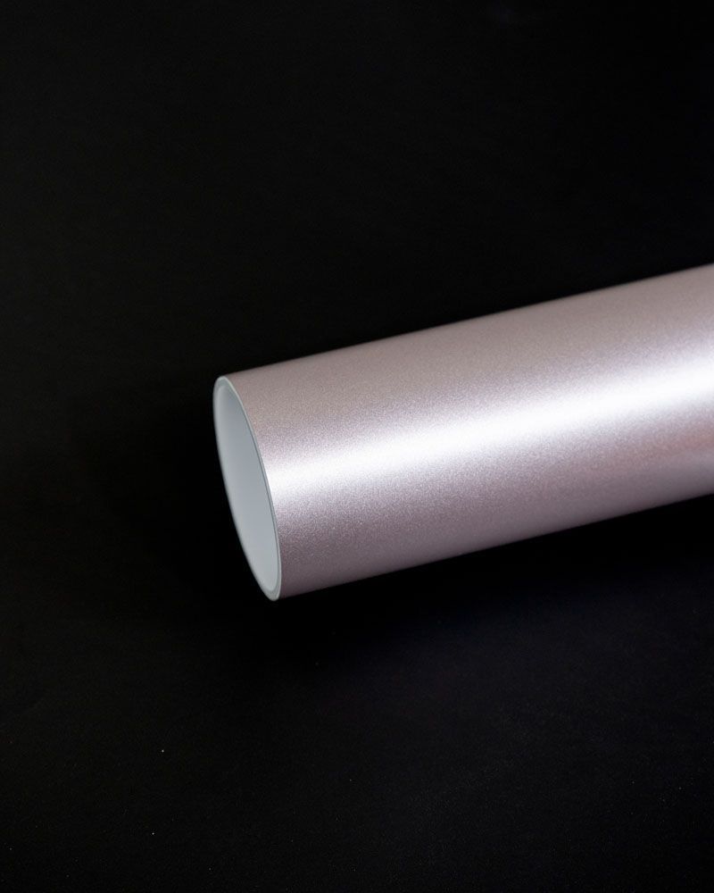 A close up of a pink metallic wrapping paper roll on a black surface.