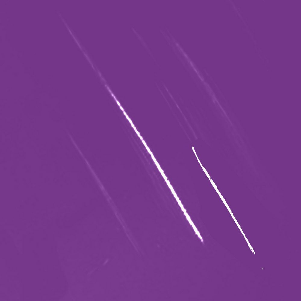 Bright white streaks across a purple background, possibly meteor trails in the sky.