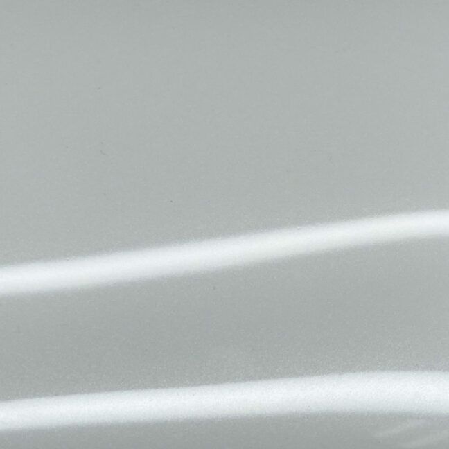 A shadow of a person is cast on a white wall.
