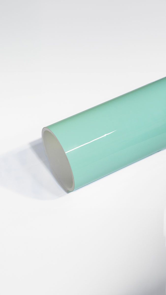A close up of a light green tube on a white surface.