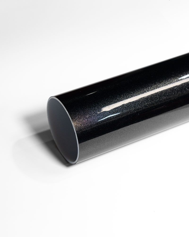 A close up of a black pipe on a white surface.