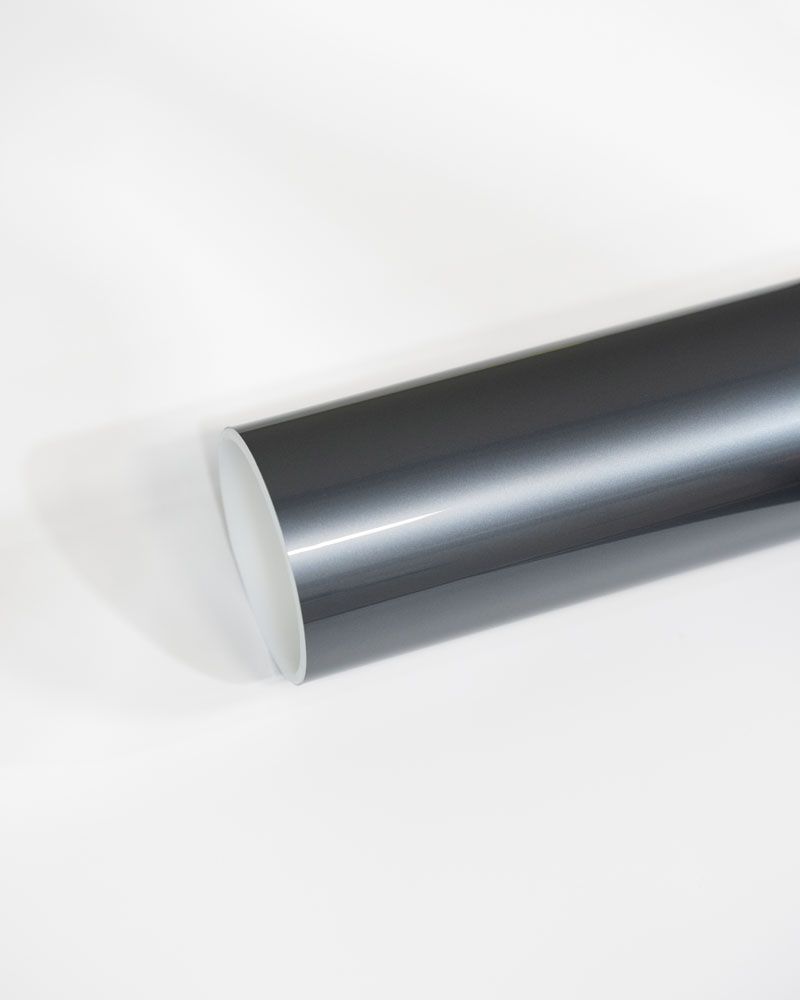 A close up of a roll of black vinyl wrap on a white surface.