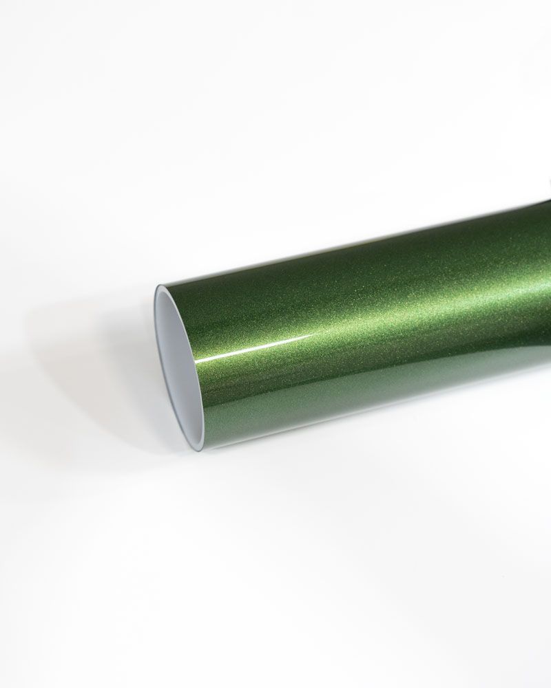 A close up of a green wrapping paper roll on a white surface.