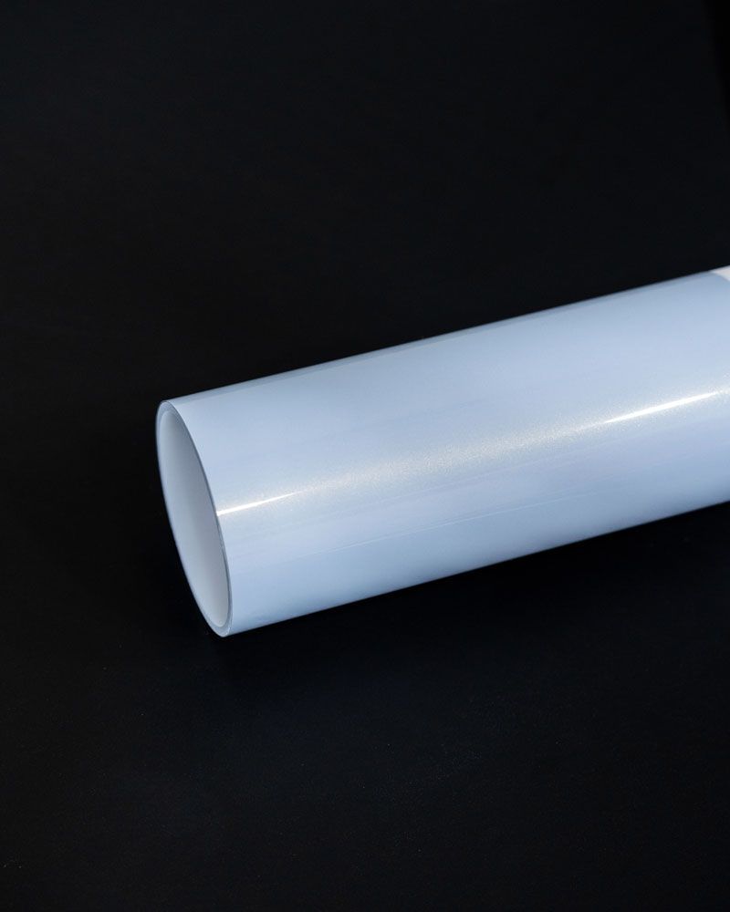 A white plastic pipe is sitting on a black surface.
