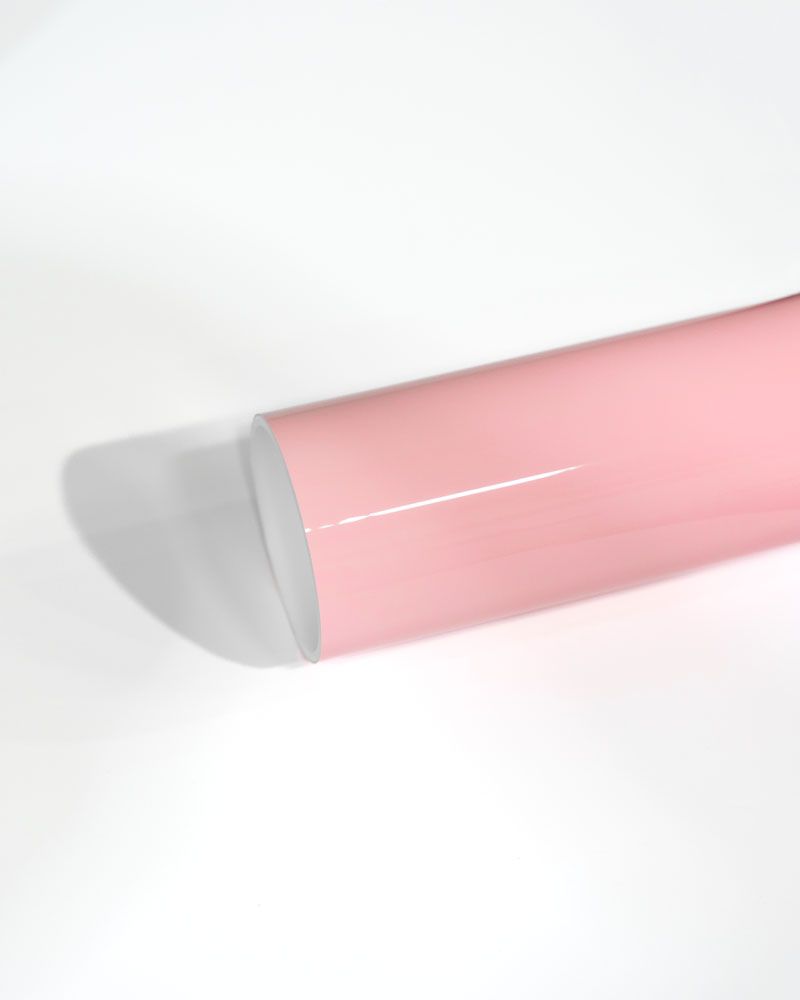 A roll of pink vinyl wrap is sitting on a white surface.