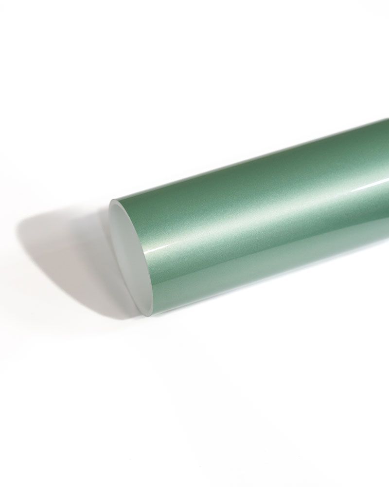 A green roll of vinyl wrap is sitting on a white surface.
